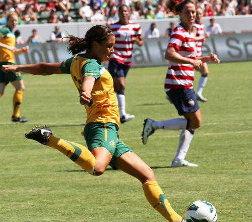 a woman soccer player kicks a ball